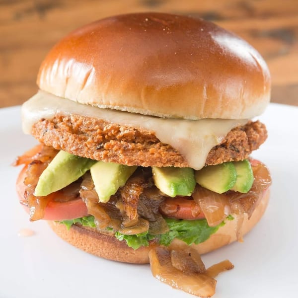 A Sizzlin City Burger with a crispy patty, melted cheese, avocado, caramelized onions, and lettuce.